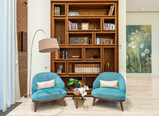 Two blue chairs with a bookcase in the background set up by an airbnb interior designer